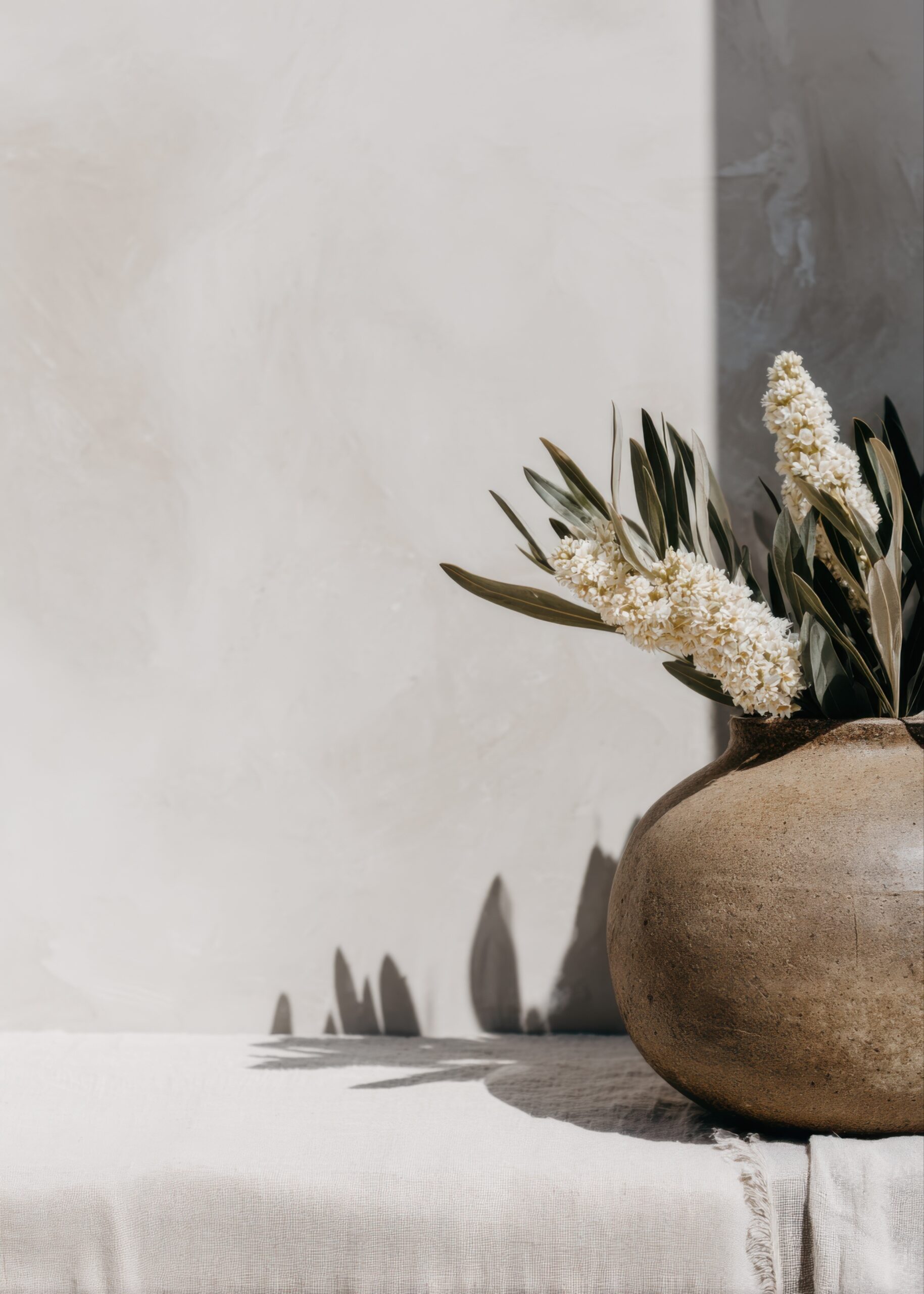 Decoratieve bruine vaas met witte lila takken in boho-stijl, symbool voor groei en de persoonlijke tijdlijn van Géraldine Auguste bij Mindful Living Therapeutics.