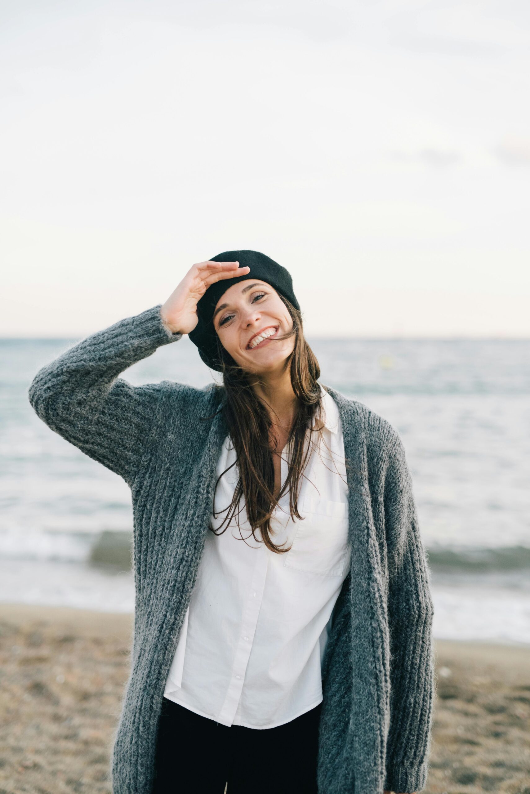 reis-naar-welzijn-vrouw-strand-mindful-living-therapeutics Blije vrouw op het strand die geniet van vrijheid en een pijnvrij leven door holistische therapie.